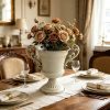 White-urn-vase-used-as-a-holiday-table-centerpiece-on-a-plaid-runner-with-candles-and-Christmas-decorations