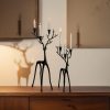 Black minimalist reindeer candle holders with lit taper candles, front view.