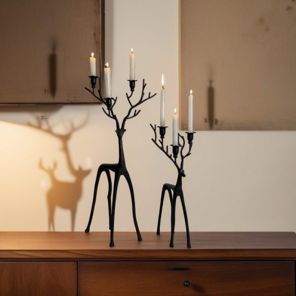 Black minimalist reindeer candle holders with lit taper candles, front view.