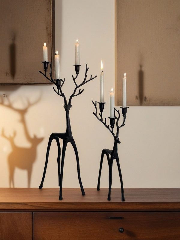 Black minimalist reindeer candle holders with lit taper candles, front view.